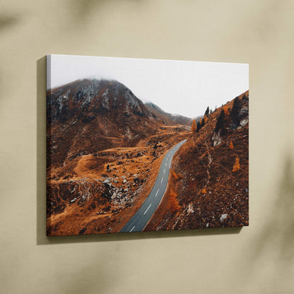 Autumn road winding through vibrant orange and brown fall foliage on canvas wall art.
