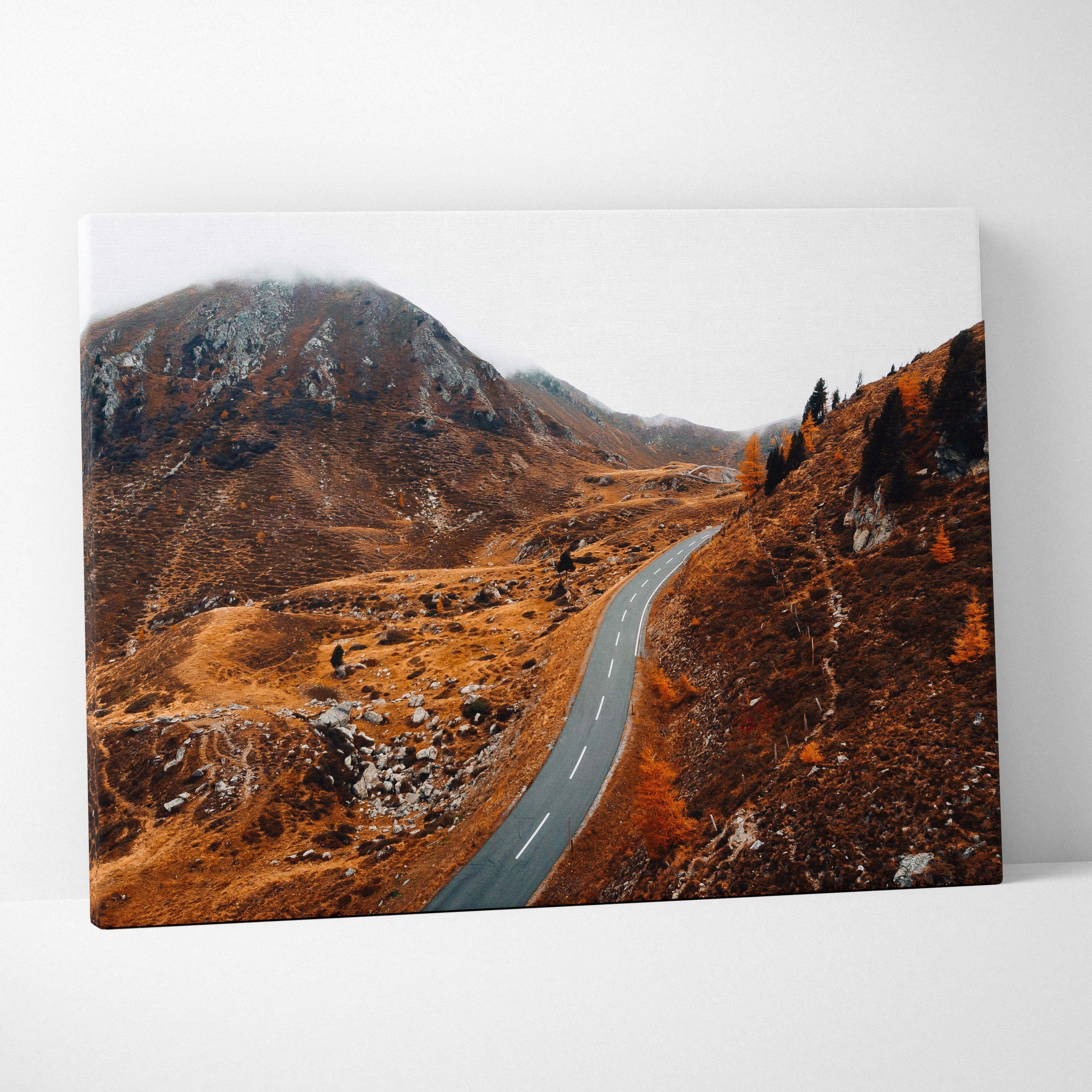 Canvas wall art featuring a winding road through rugged autumn mountains with brown foliage.