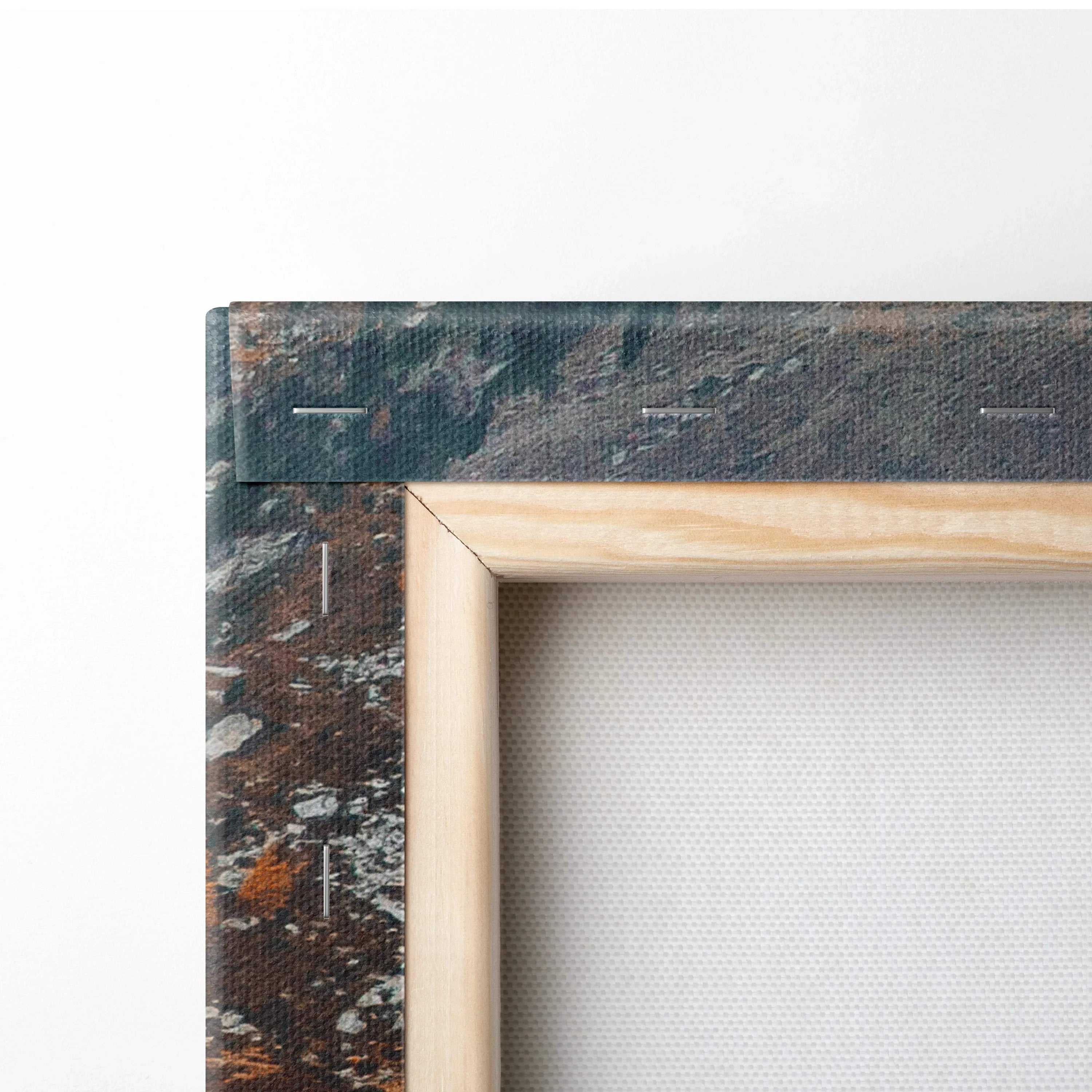 Close-up of wooden frame corner on textured white canvas art with dark abstract painted edges.