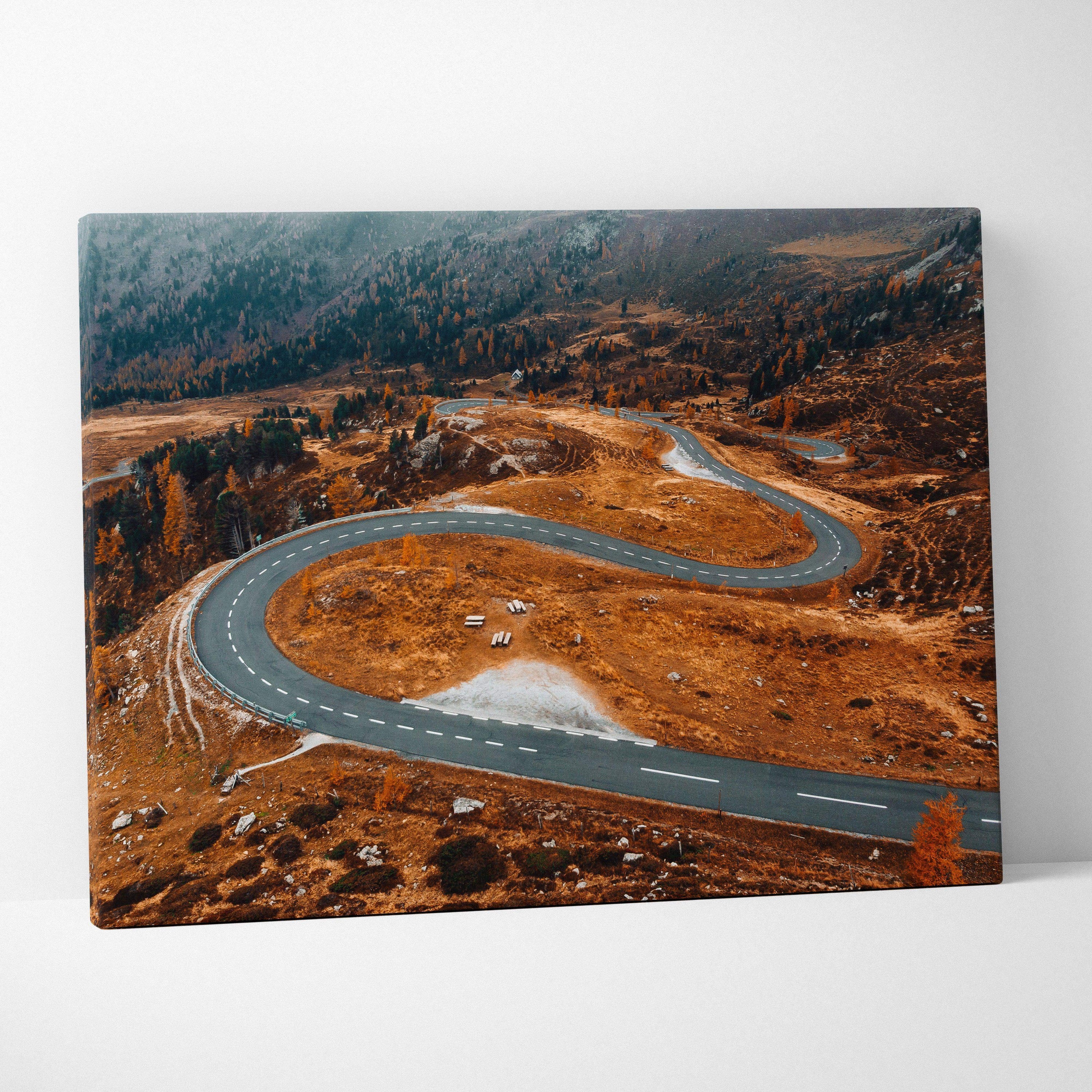 Autumn winding road through vibrant orange and brown foliage on canvas wall art.