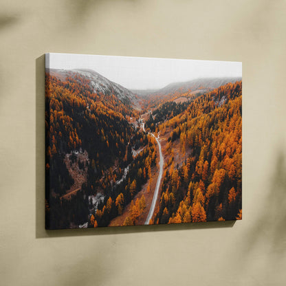 Autumn road winding through vibrant orange and red forest on canvas wall art.