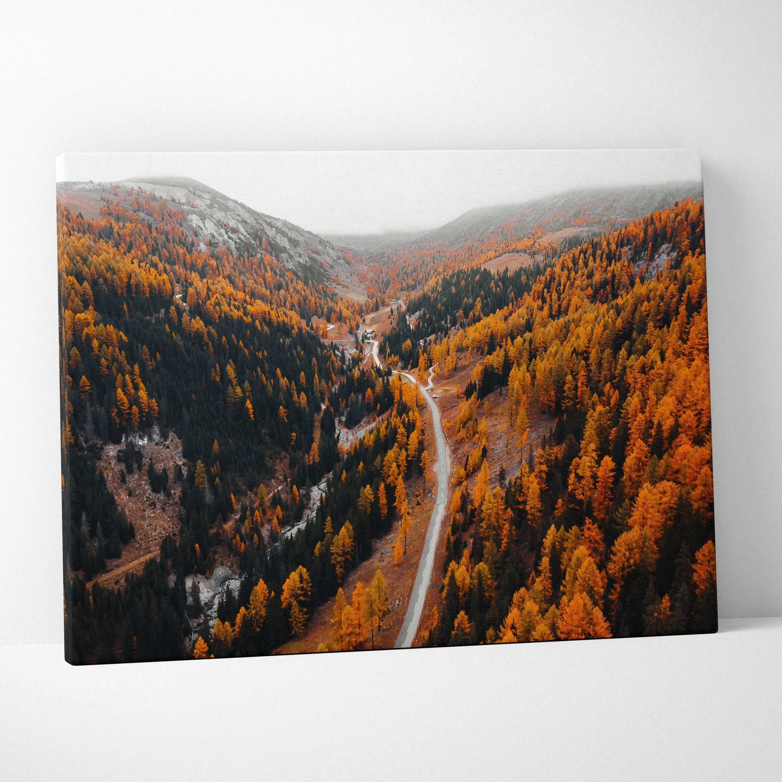 Autumn road winding through vibrant orange foliage under a foggy sky canvas wall art.