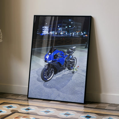 Yamaha R1 motorcycle poster in blue and black framed wall art leaning against white wall on tiled floor.