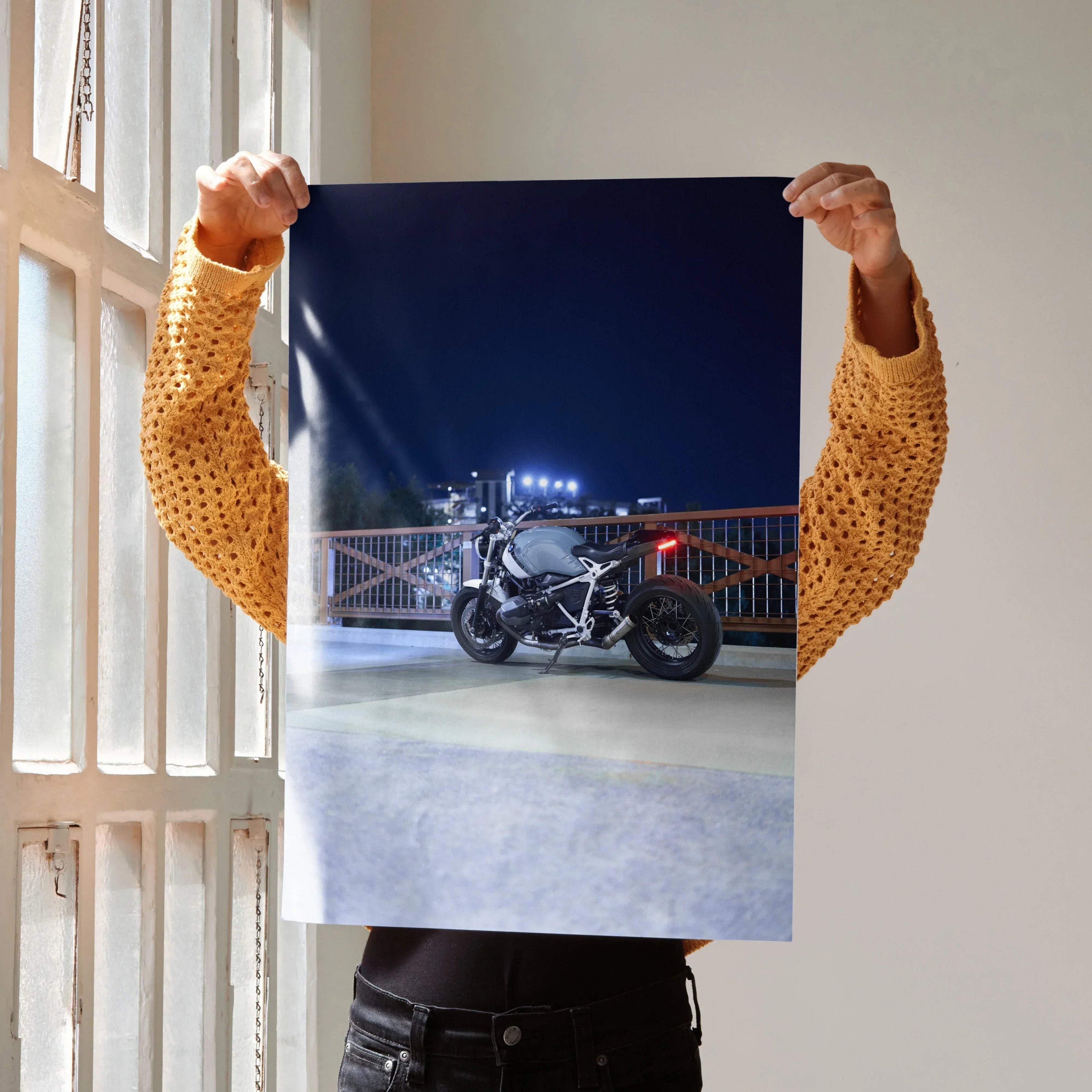 BMW R Nine T motorcycle Night Ride poster with dark blue night sky, streetlight reflections, and urban bridge background.