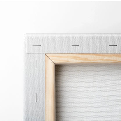 Close-up of stretched white canvas fabric on wooden frame with visible staples, corner joint detail for wall art.