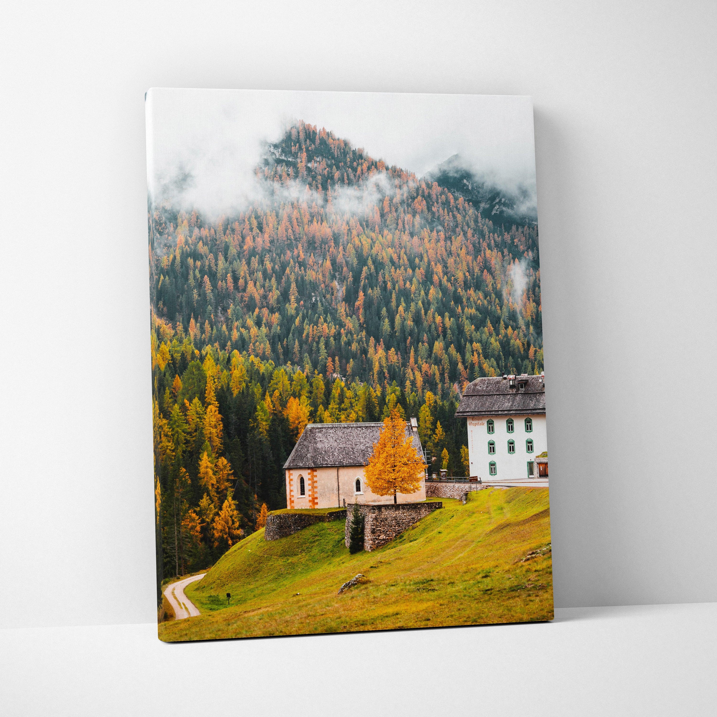 Canvas wall art featuring a misty mountain landscape with autumn trees and traditional alpine buildings.