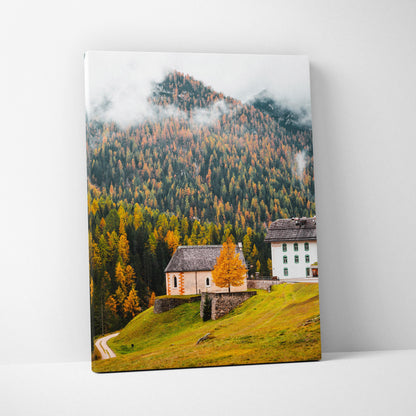 Canvas wall art featuring a misty mountain landscape with autumn trees and traditional alpine buildings.