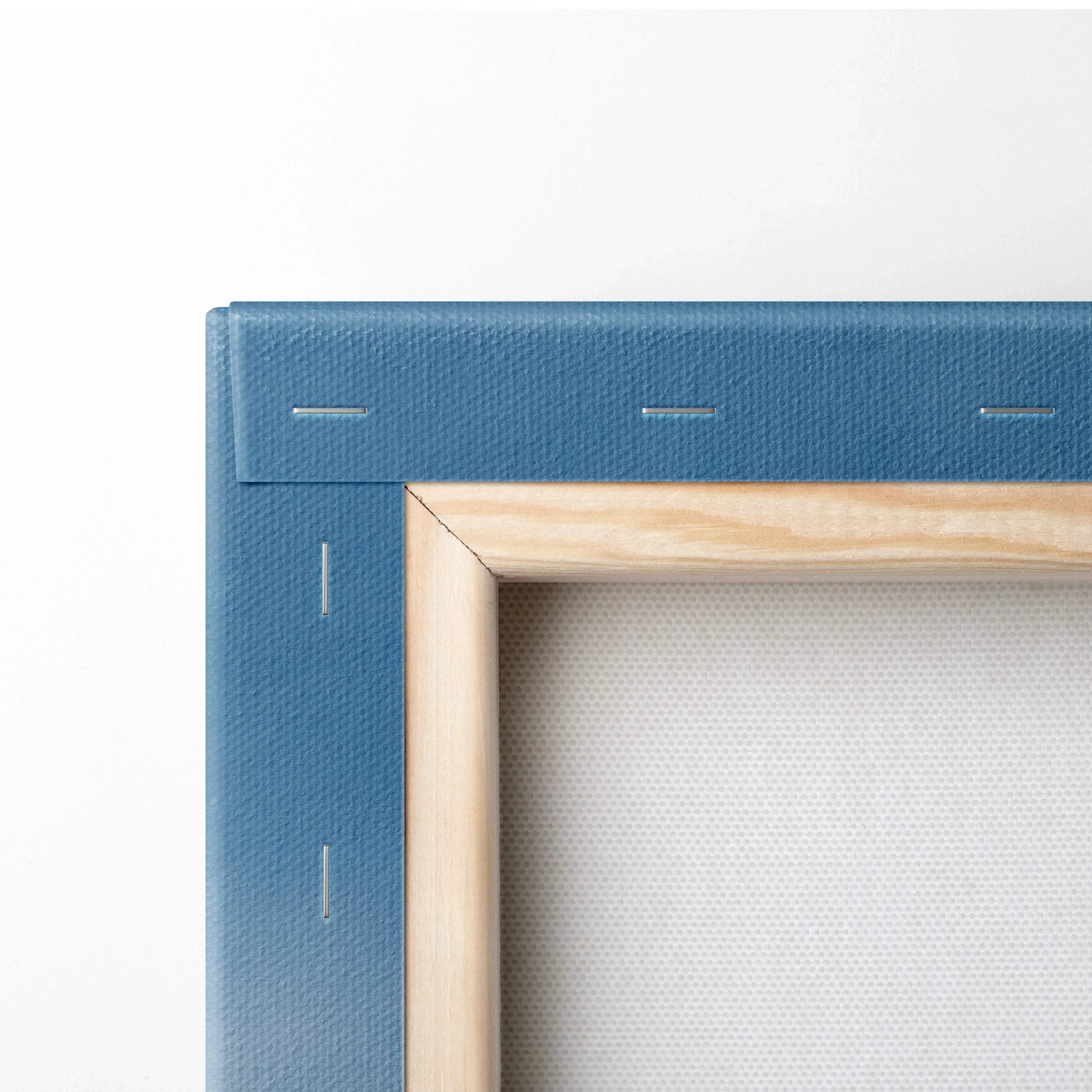 Close-up of wooden frame corner on white canvas stretched over blue backing with stapled edges.