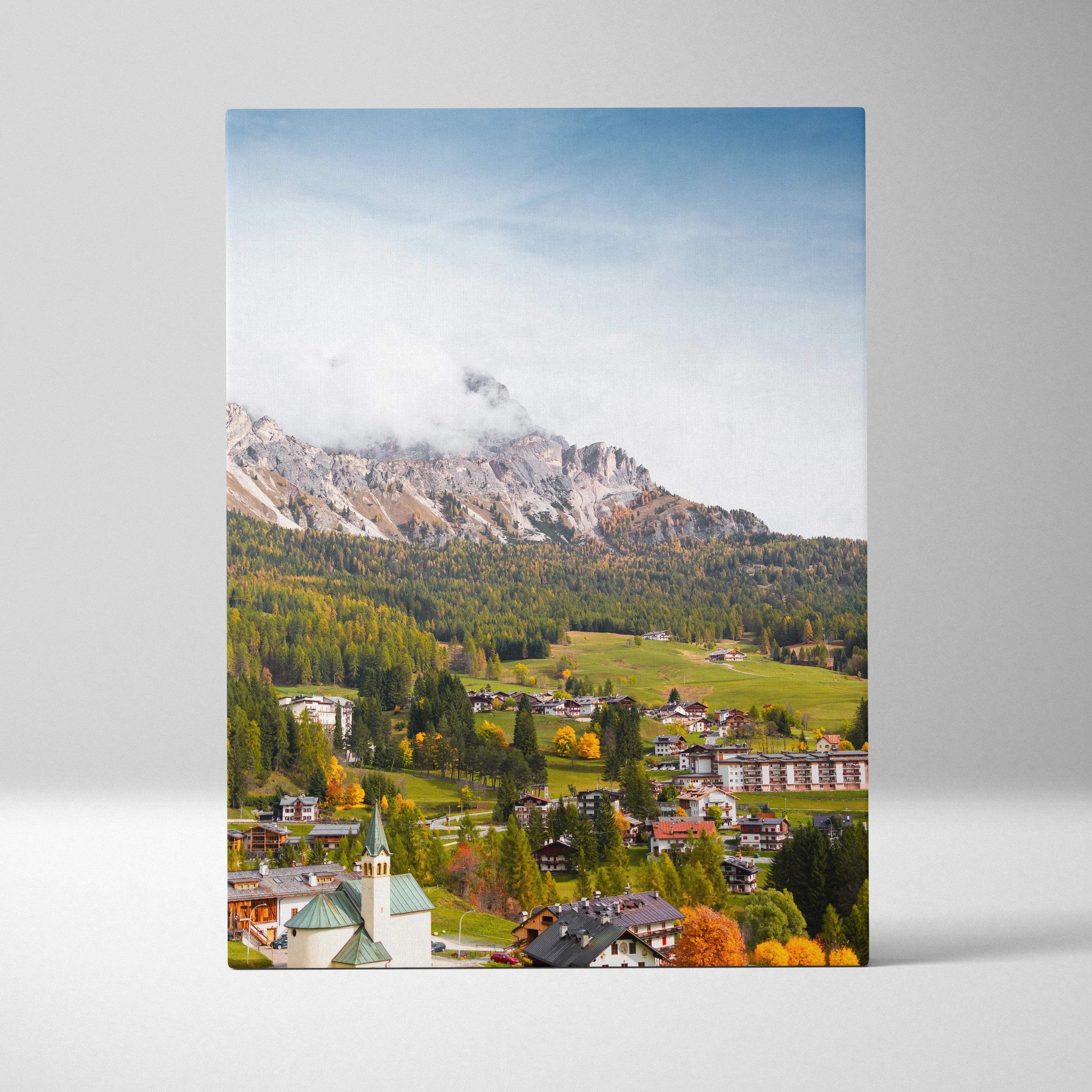 Vertical canvas art wall print of scenic mountain village with autumn foliage and blue sky.
