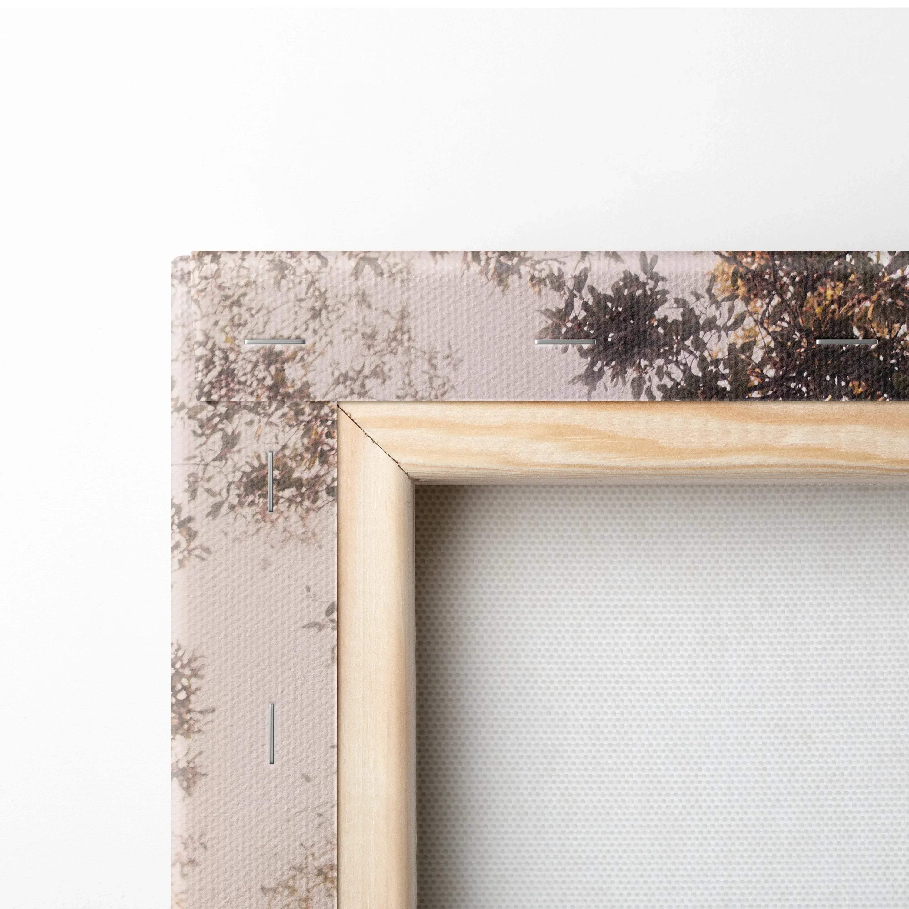 Close-up of natural wood frame and textured fabric canvas wall art with muted tree branch print.