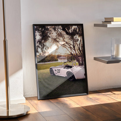 Shelby Cobra #002 poster wall art showing white classic car under sunset with trees and grassy field.