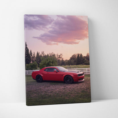 Red Dodge Challenger Hellcat parked near white fence at sunset canvas wall art.