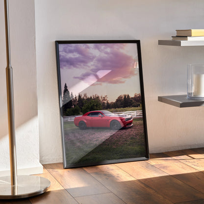 Dodge Challenger Hellcat in red at sunset poster framed as wall art leaning against wall on wooden floor.