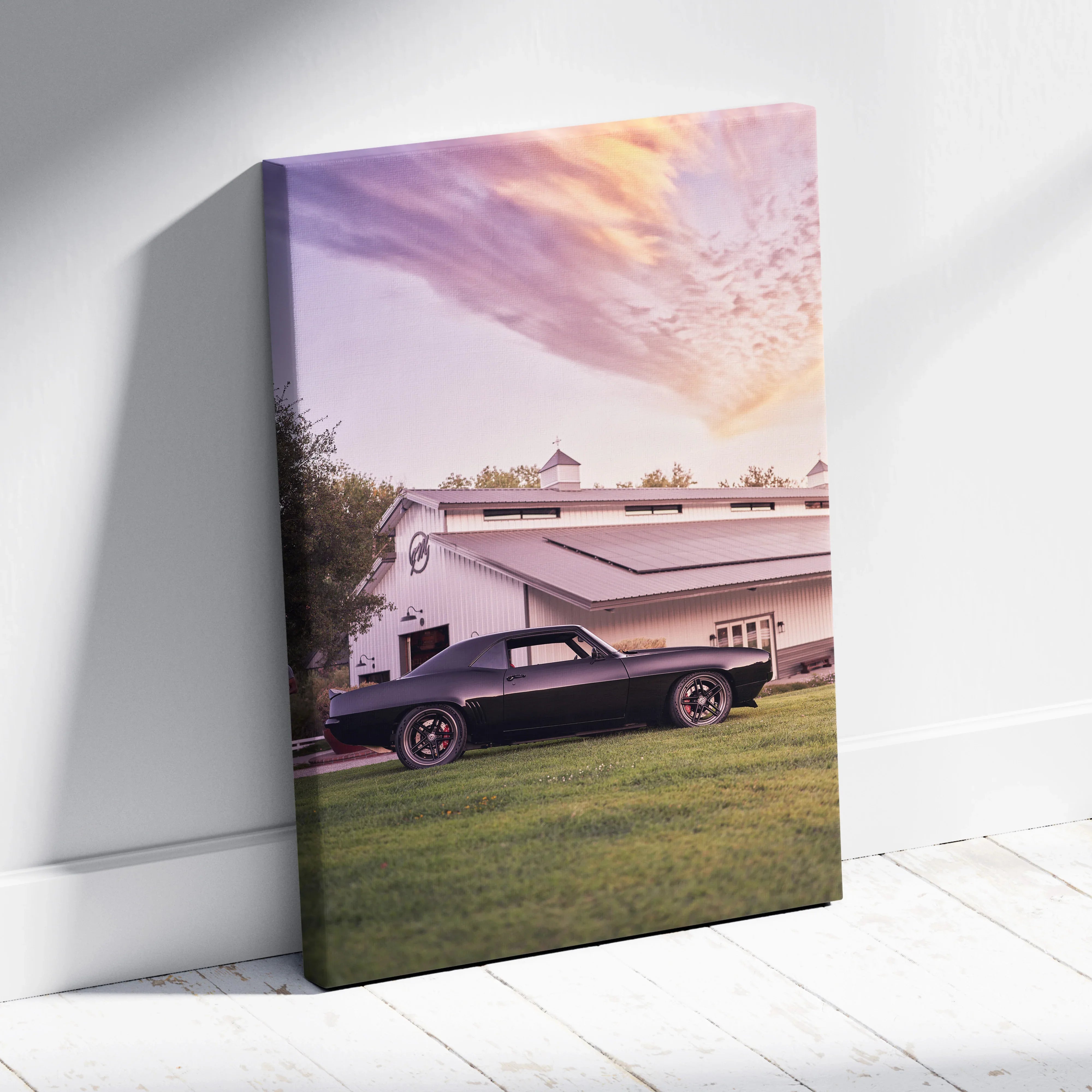 1969 Camaro parked on grass in front of white building under vibrant sunset sky canvas wall art.