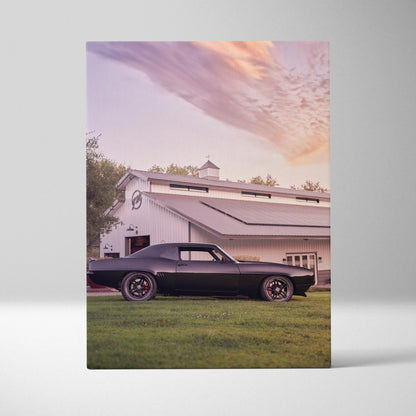 1969 black Camaro in front of white barn under colorful sunset sky canvas wall art.