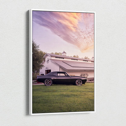1969 black Camaro parked on grass with barn and colorful sunset sky vertical canvas wall art.