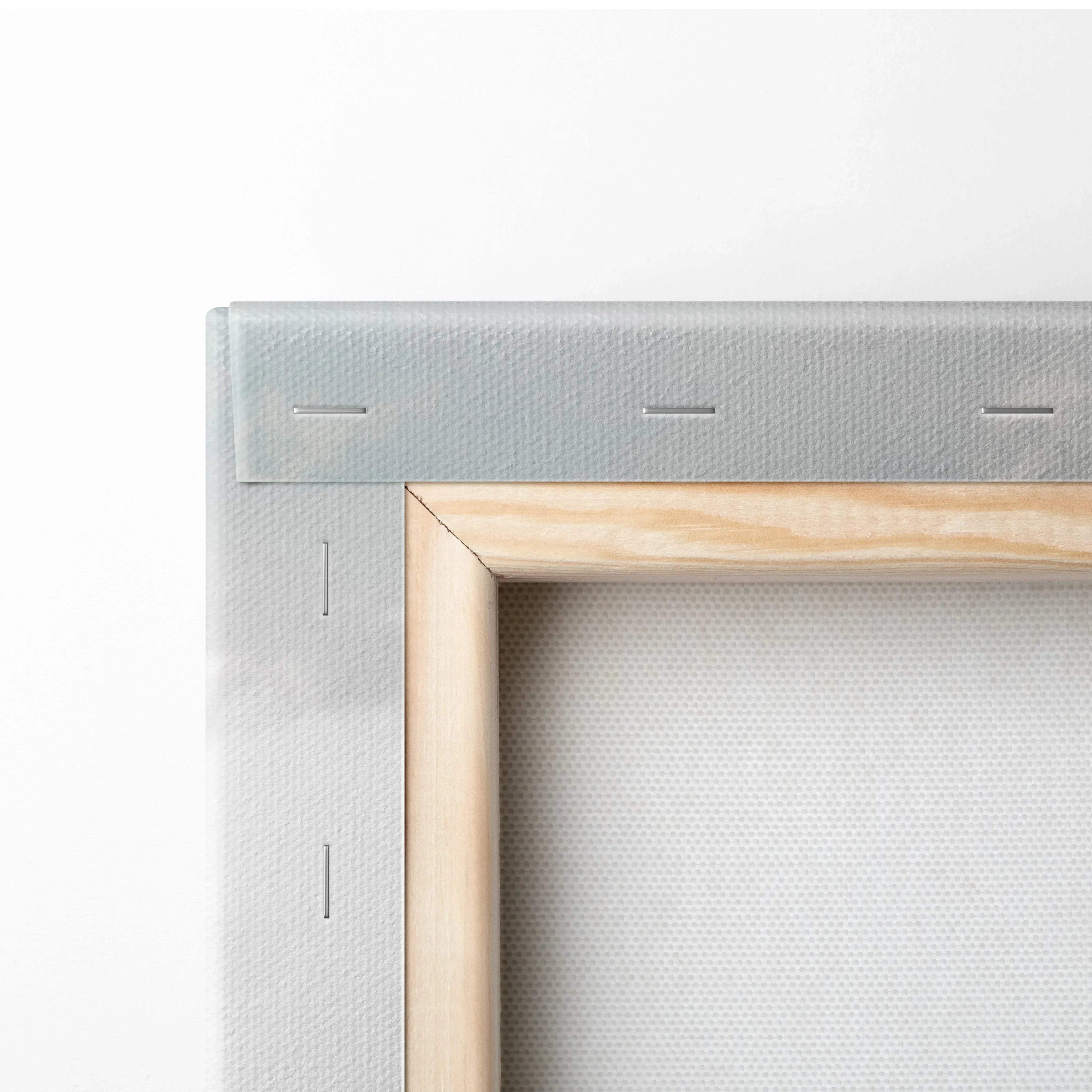 Close-up of stretched beige canvas over wooden frame with visible staples on back corner.