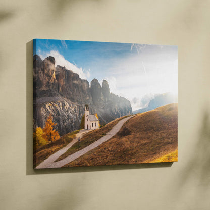 Canvas wall art featuring a small white chapel on a winding path against rocky mountains and a blue sky.