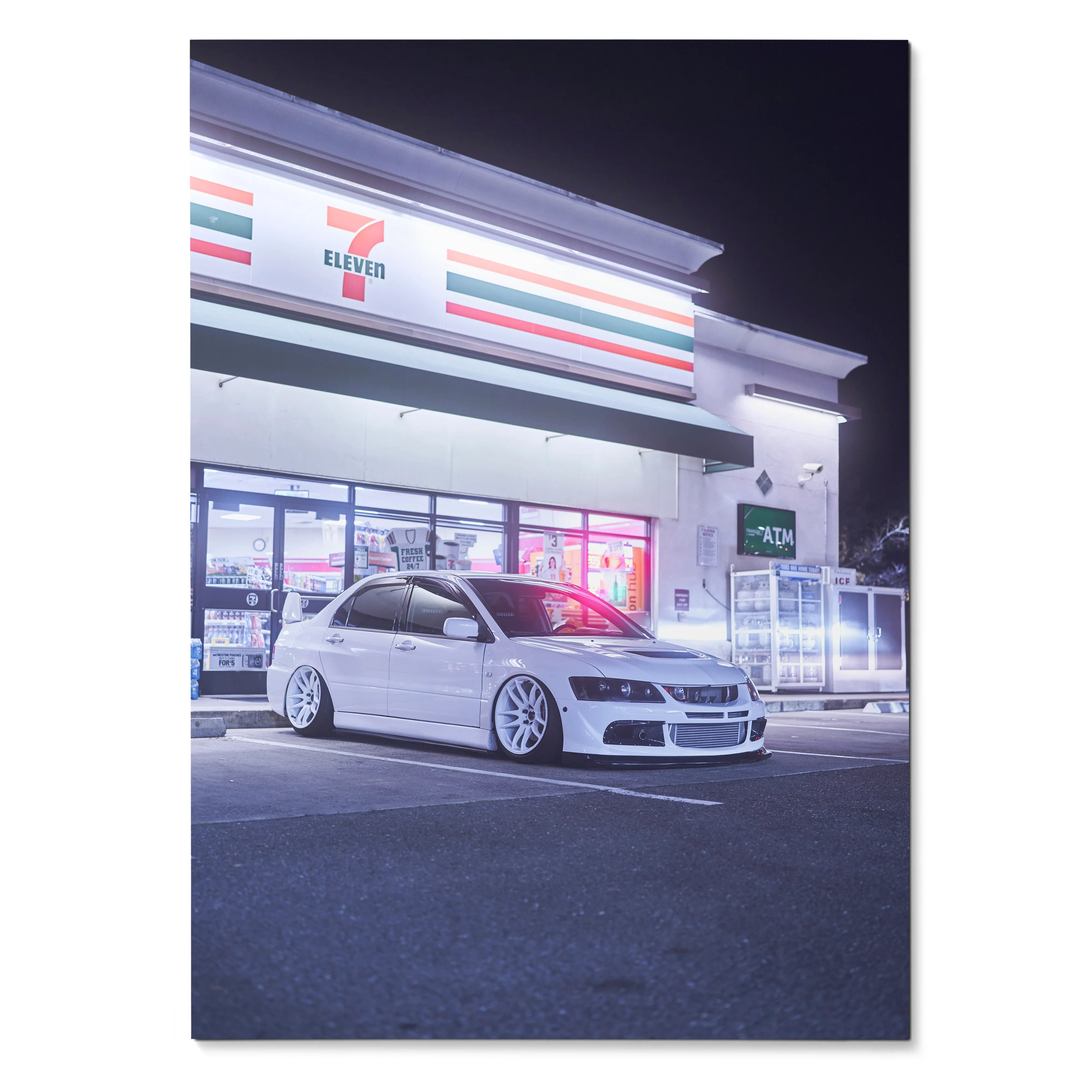 White Mitsubishi Evo 8 parked outside illuminated 7-Eleven at night poster wall art.