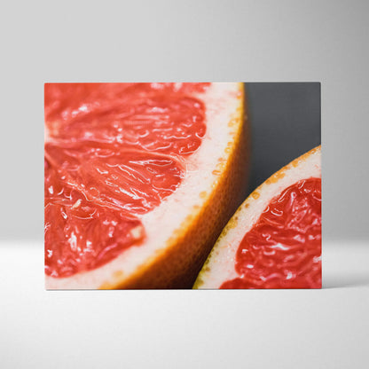 Close-up canvas wall art featuring vibrant red grapefruit slices with textured rind against a dark background.