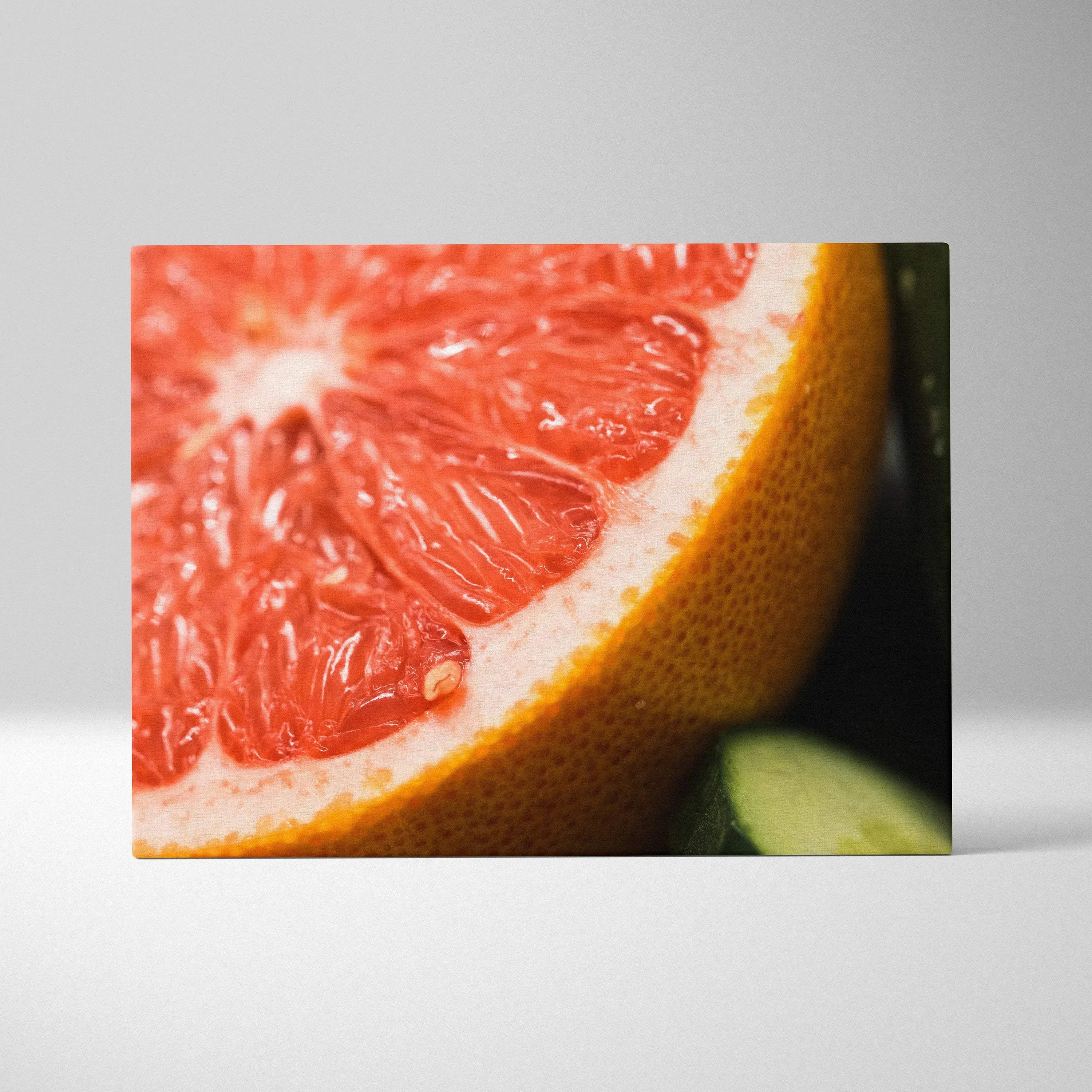 Close-up canvas print of a vibrant red grapefruit slice with textured skin, modern wall art decor.