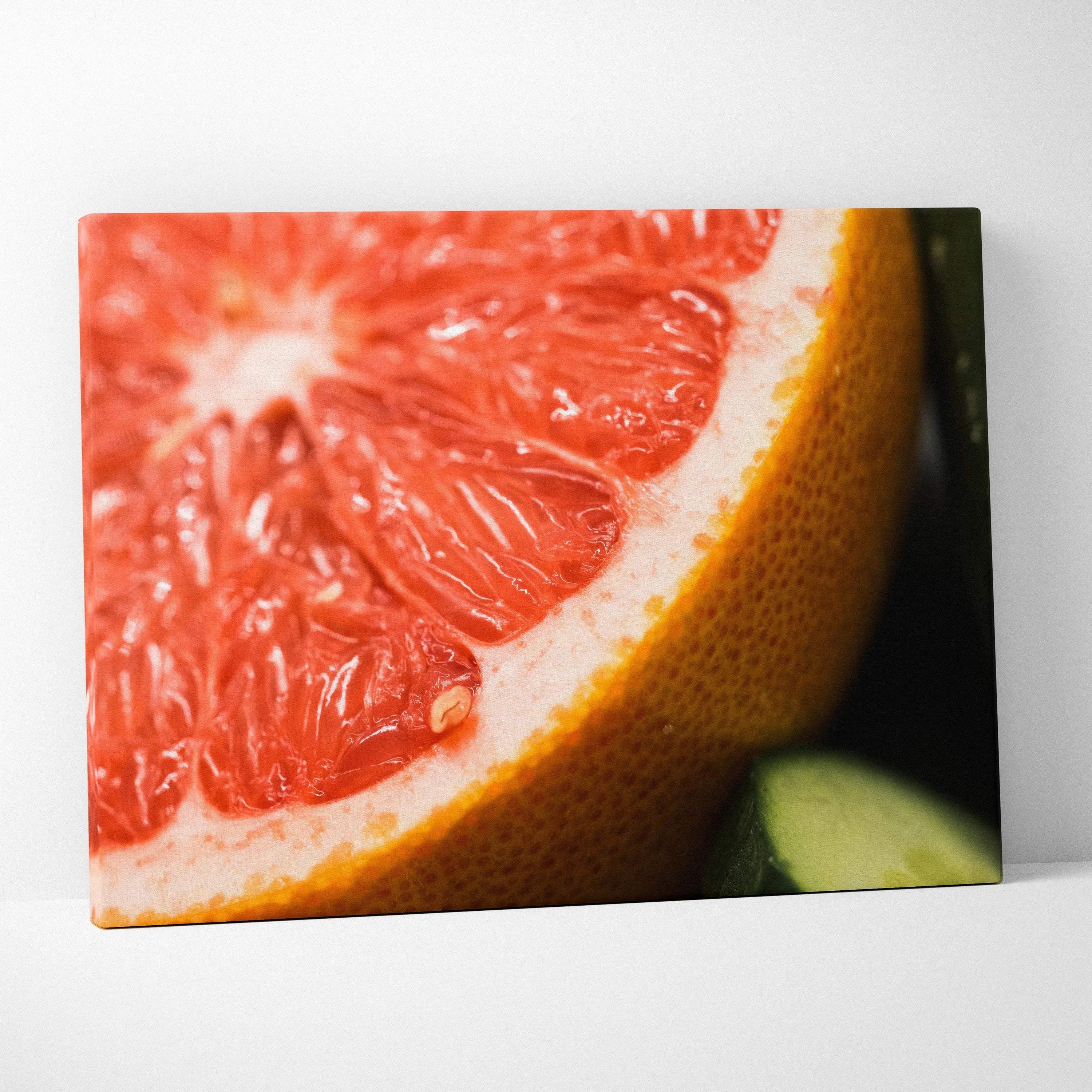 Close-up canvas wall art of a vibrant pink grapefruit slice with detailed texture and bright yellow rind.