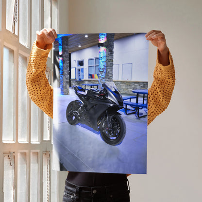Yamaha R6 black motorcycle poster held up as wall art with urban nighttime backdrop.