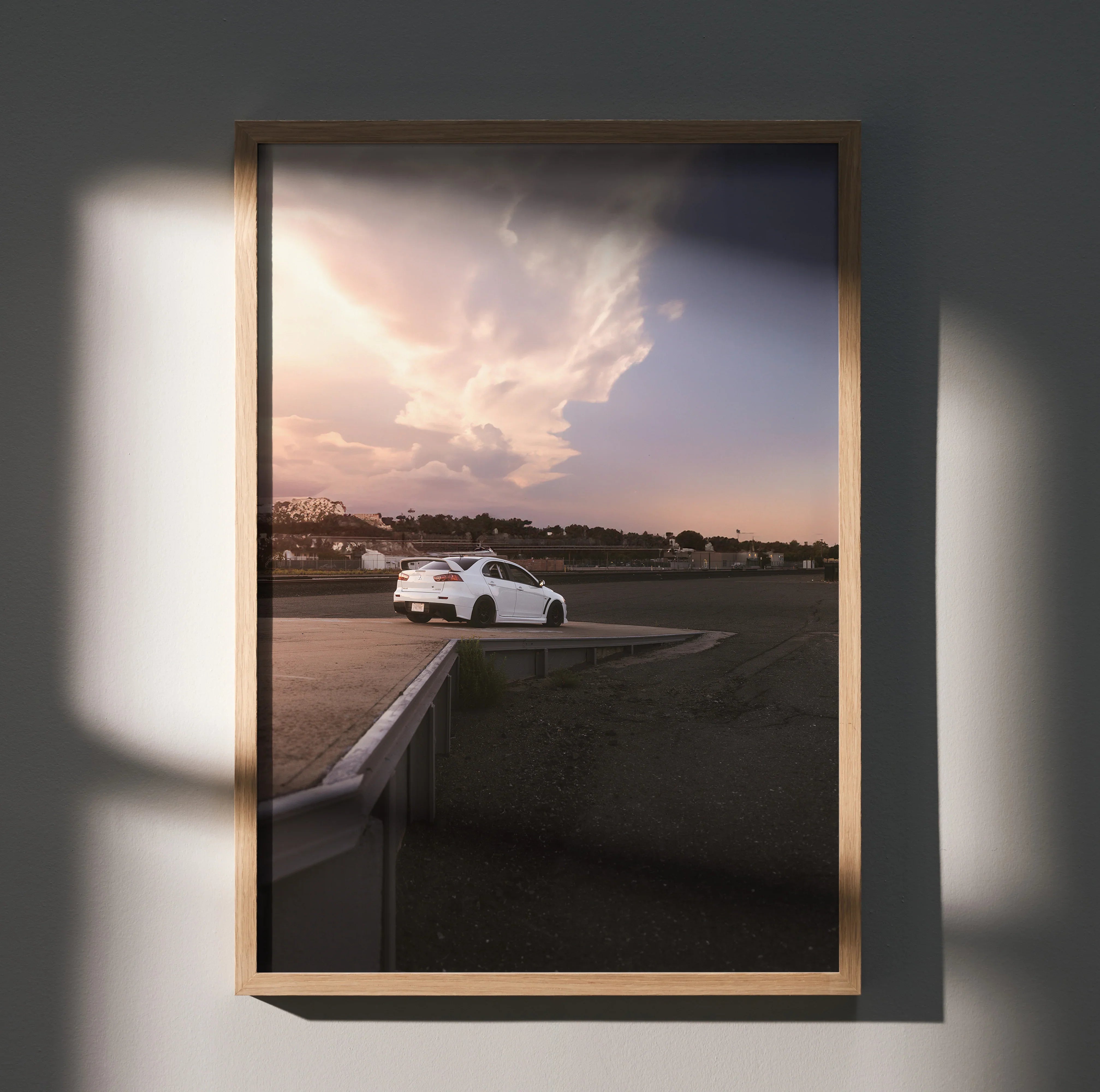 Mitsubishi Evo 10 poster wall art with sunset sky and car on racetrack in wooden frame.
