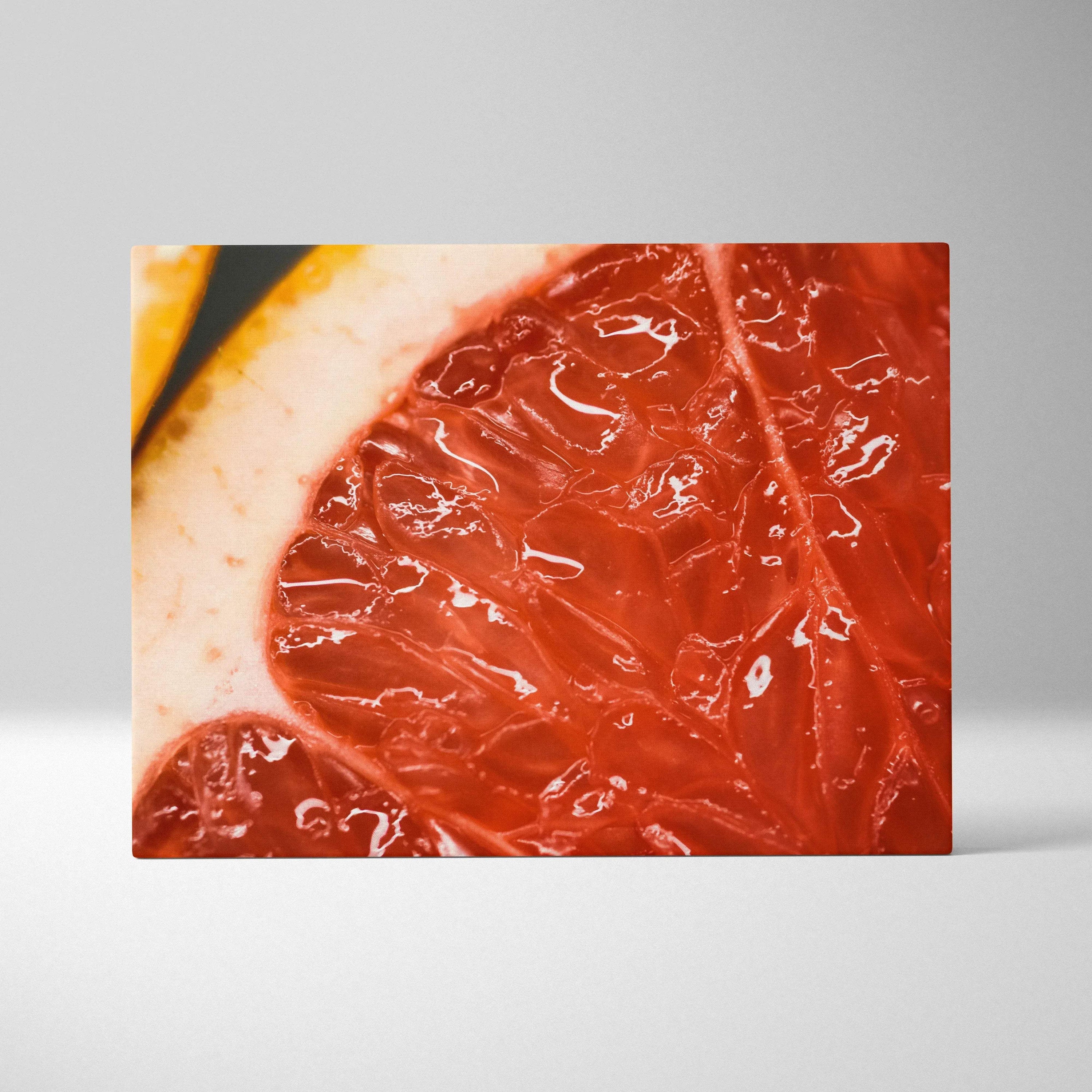 Close-up canvas wall art print featuring a juicy red grapefruit slice with vibrant orange and yellow tones and detailed pulp