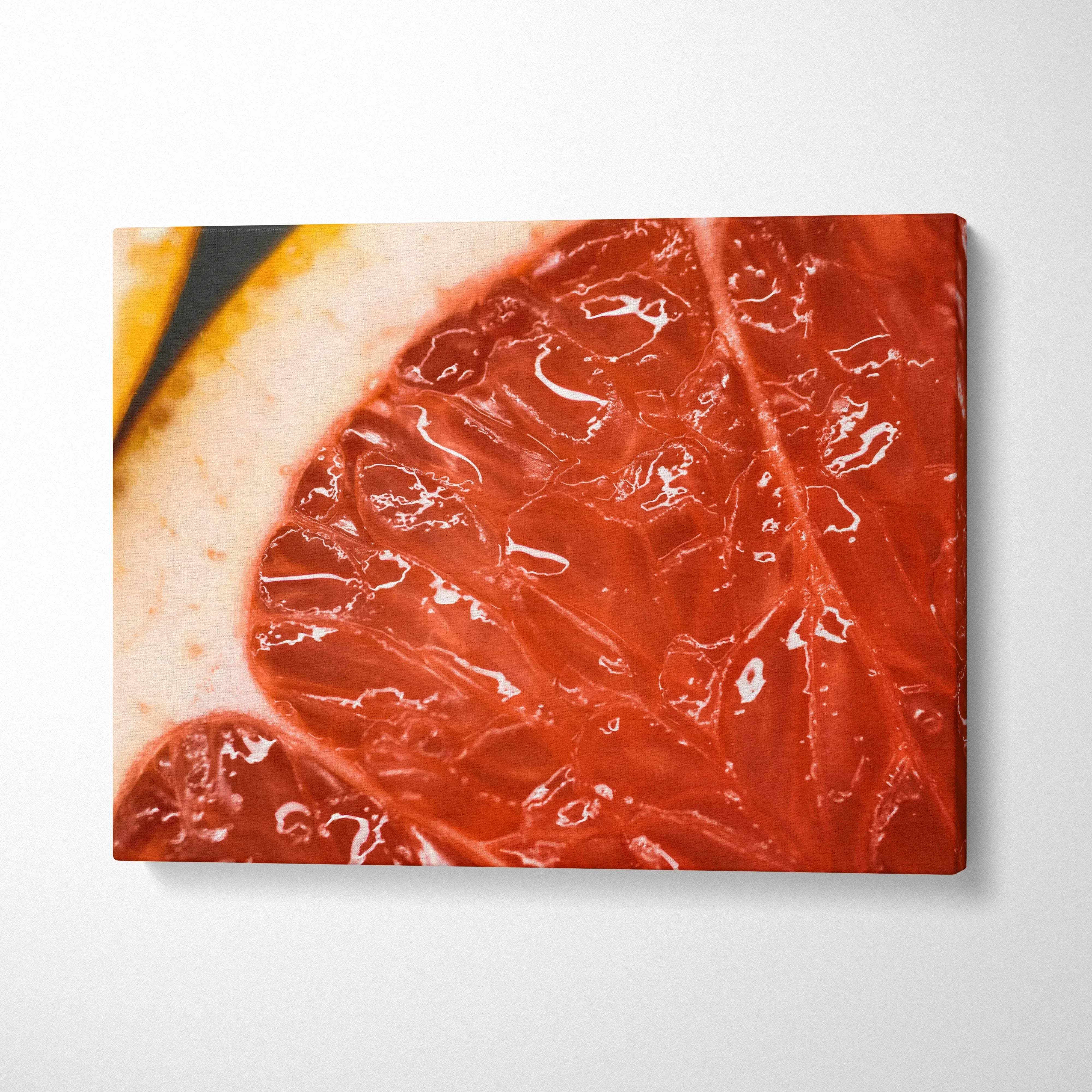 Close-up grapefruit slice canvas wall art with vibrant red and orange hues for modern decor.