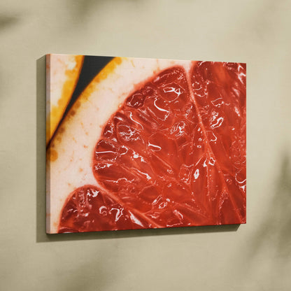 Close-up canvas wall art featuring detailed, vibrant red and pink grapefruit slices with white and yellow rind accents.