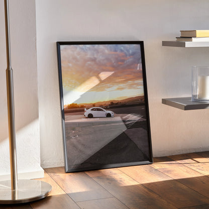 Mitsubishi Evo 10 poster wall art with sunset background in black frame on wooden floor.