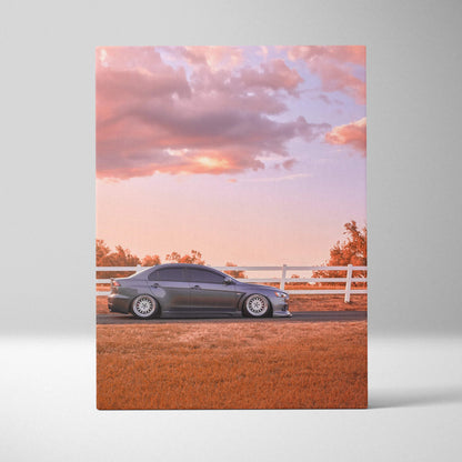 Vertical canvas wall art featuring a sleek black Mitsubishi Evo 10 against a vibrant sunset sky.