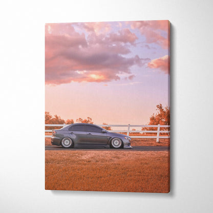Mitsubishi Evo 10 parked by white fence under pink sunset sky canvas wall art.