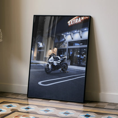 BMW S1000RR motorcycle poster leaning against wall, urban night street wall art with building background.