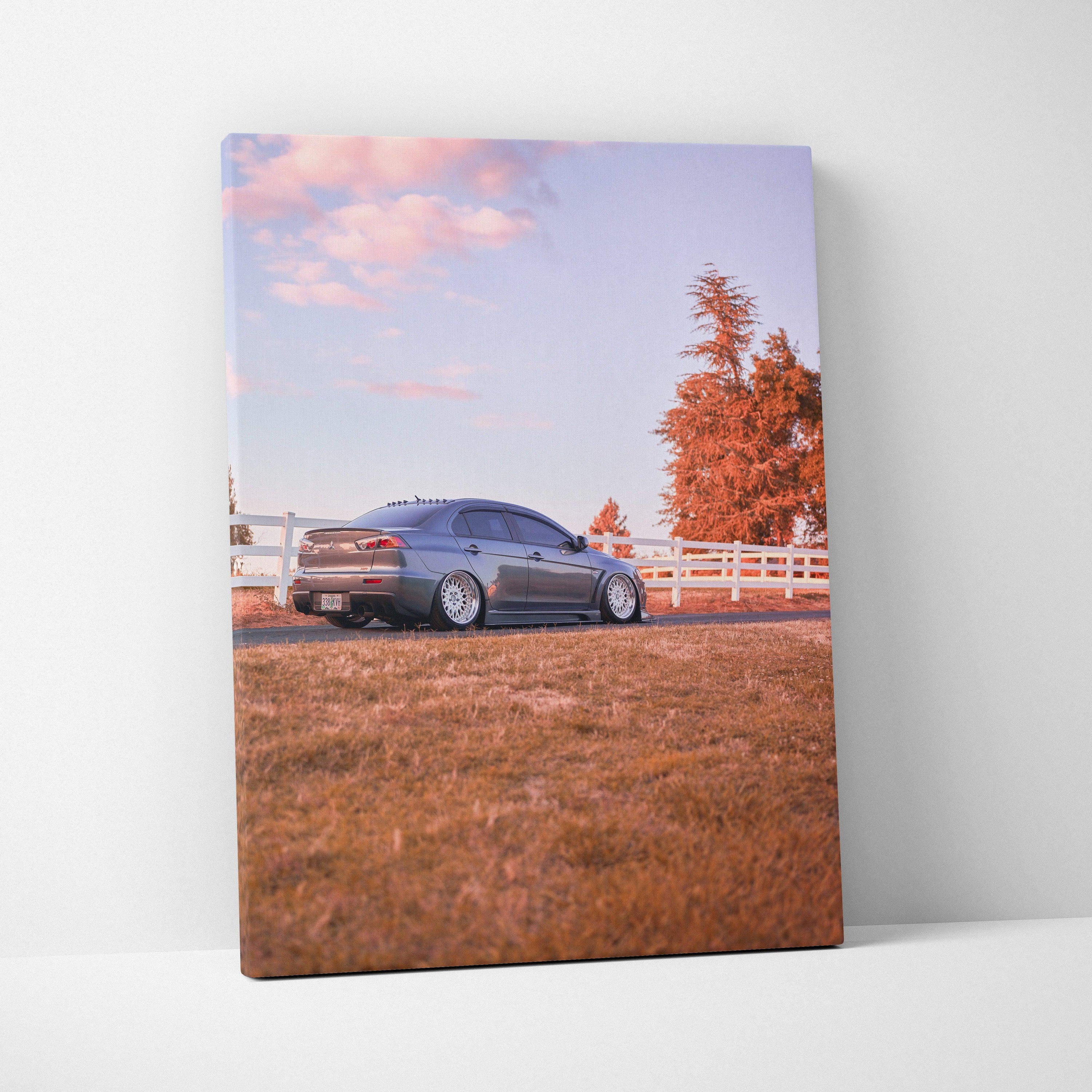 Vertical canvas wall art featuring a Mitsubishi Evo 10 parked on grass with autumn trees in the background.