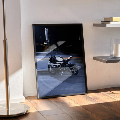 BMW S1000RR motorcycle poster wall art in black frame leaning on floor in modern room.