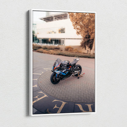 Vertical canvas wall art featuring a BMW M1000RR motorcycle parked outdoors with a blurred building background.