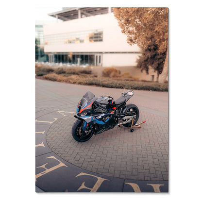 BMW M1000RR motorcycle parked on a paved road with modern building and autumn tree in the background poster wall art.