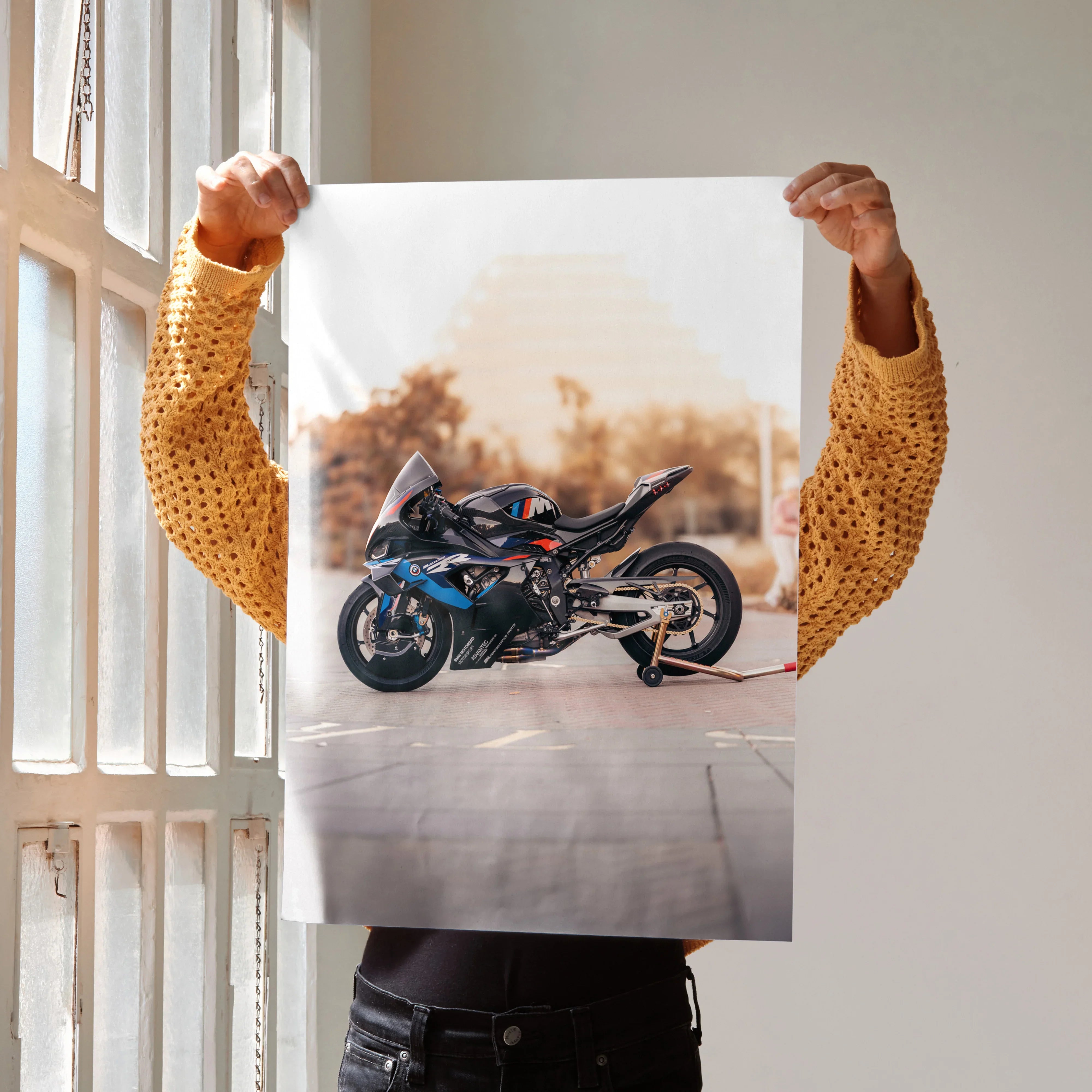 BMW M1000RR motorcycle art print poster held indoors with blurred autumn background, wall art decor.