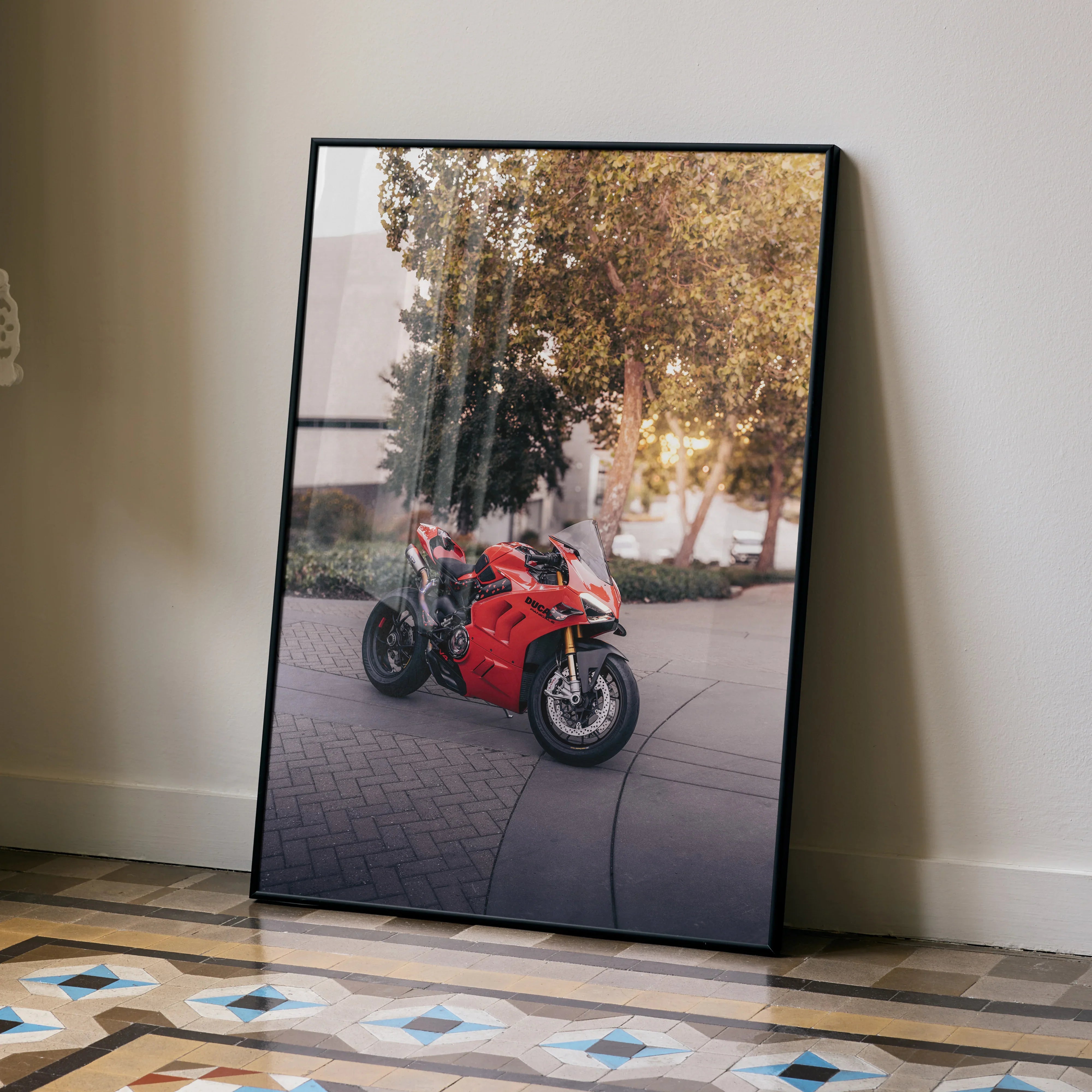 Ducati Panigale V4S red motorcycle poster leaning against wall, modern wall art with outdoor background reflection.