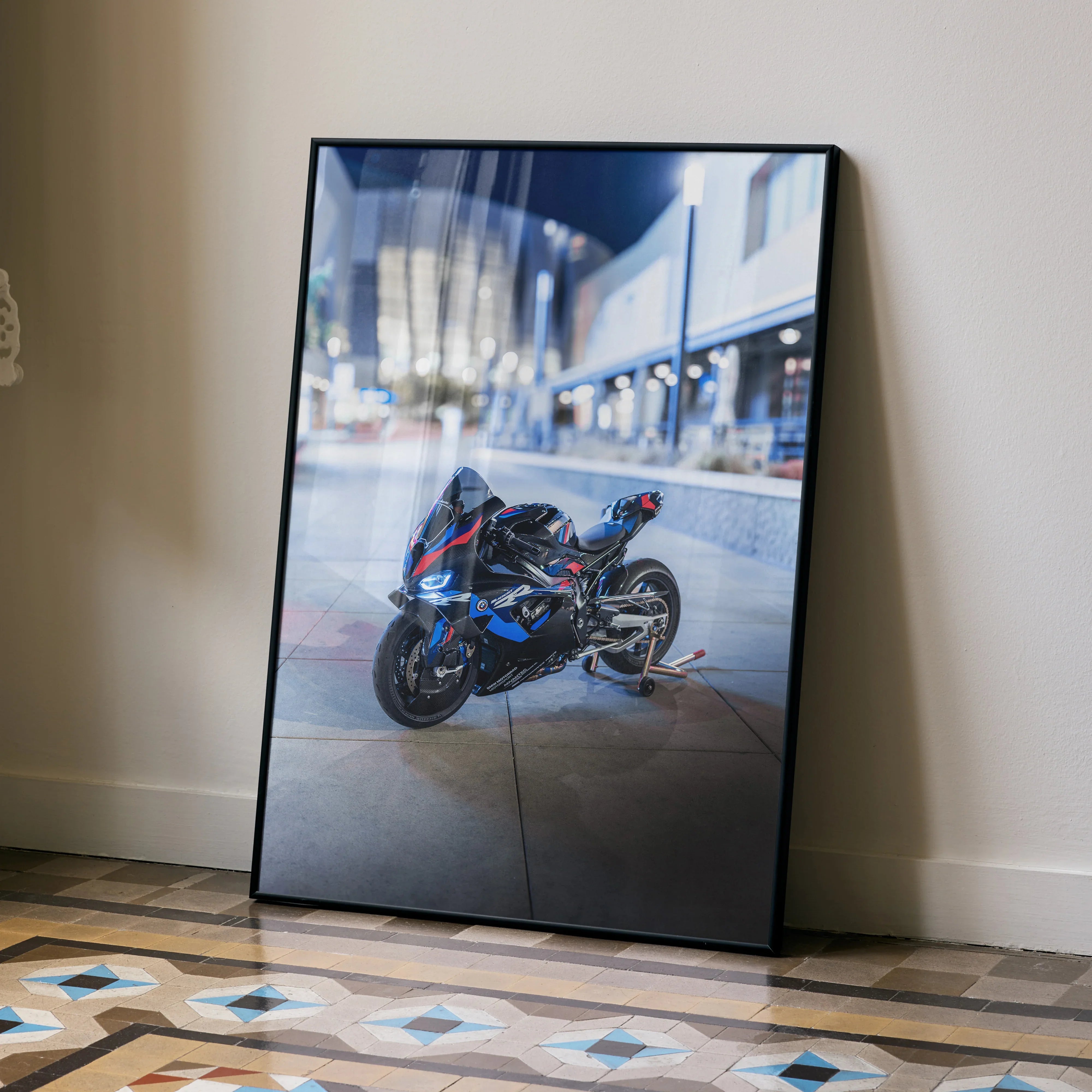 BMW M1000RR motorcycle poster with black frame leaning against wall, urban background wall art.