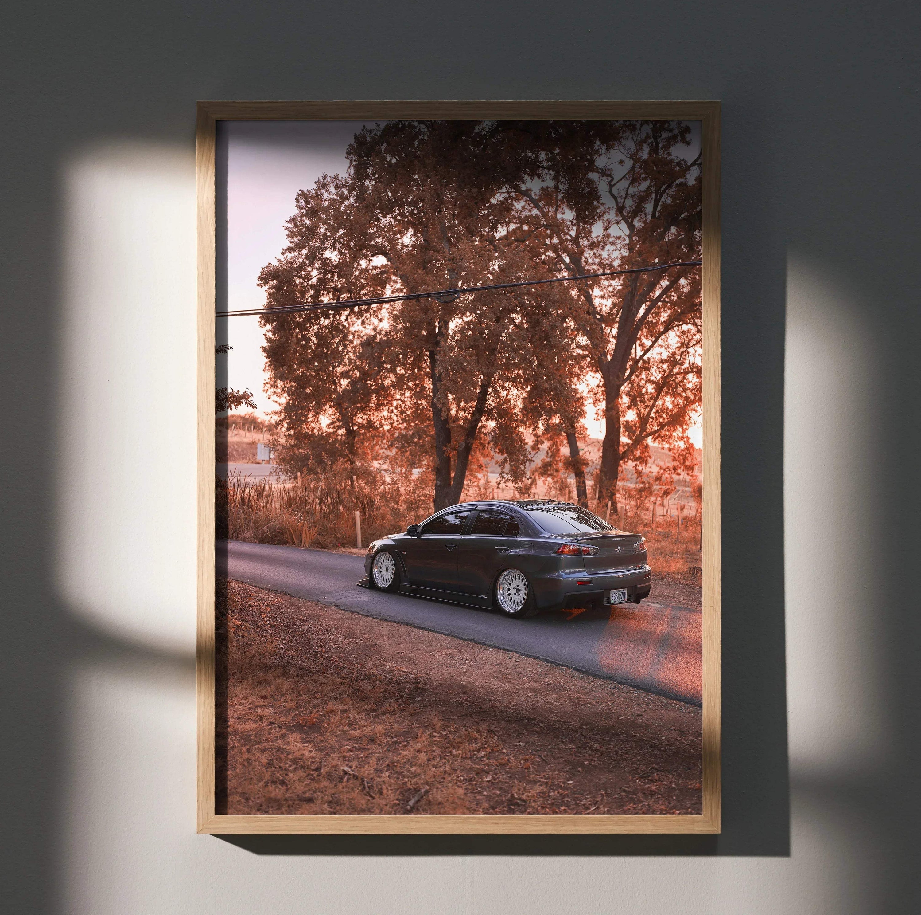 Mitsubishi Evo X poster wall art with black car on road against autumn trees in warm light.
