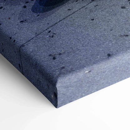 Close-up of blue textured canvas corner with subtle black speckles, vertical wall art detail.