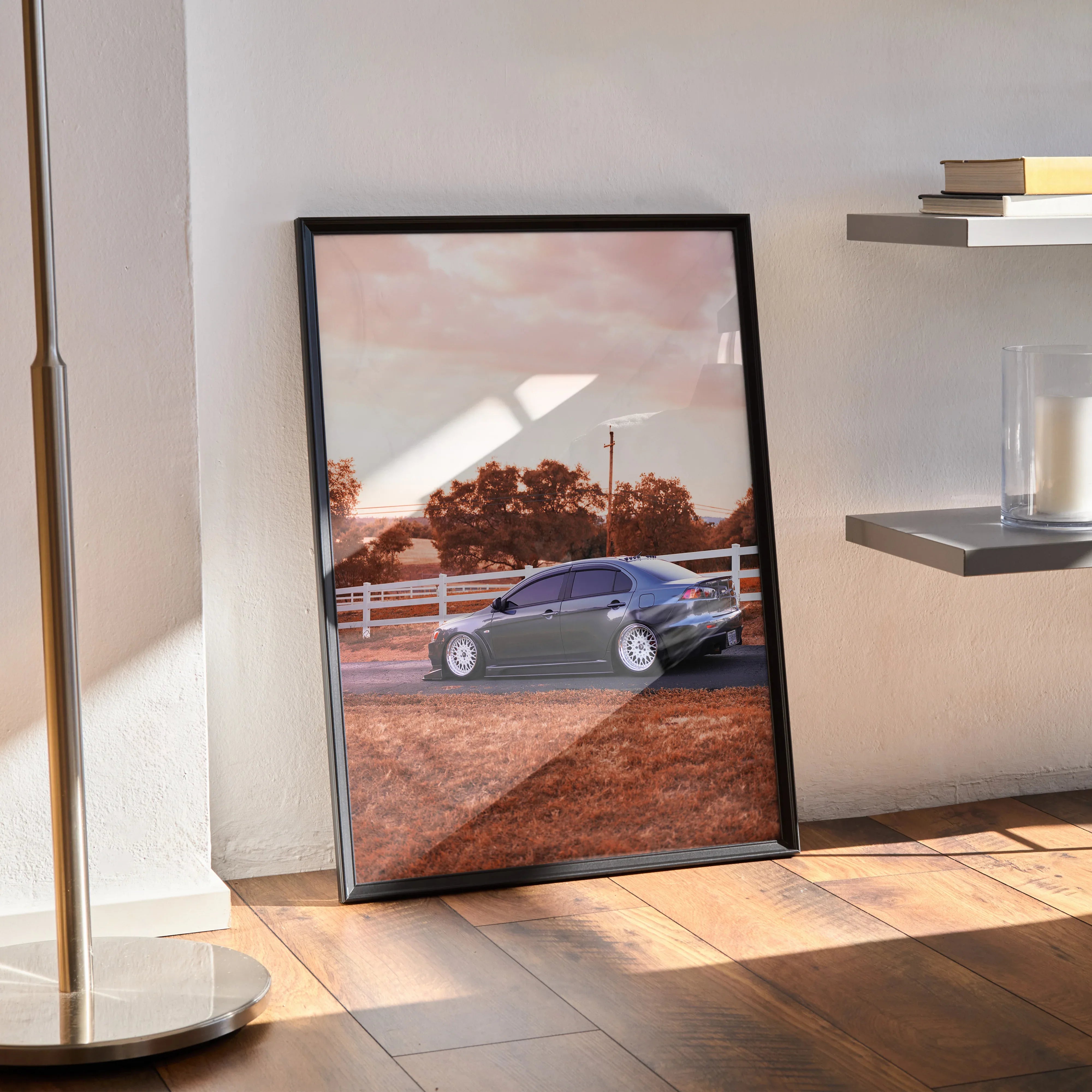 Mitsubishi Evo 10 poster in black frame leaning against wall on wooden floor, car and scenic background wall art.