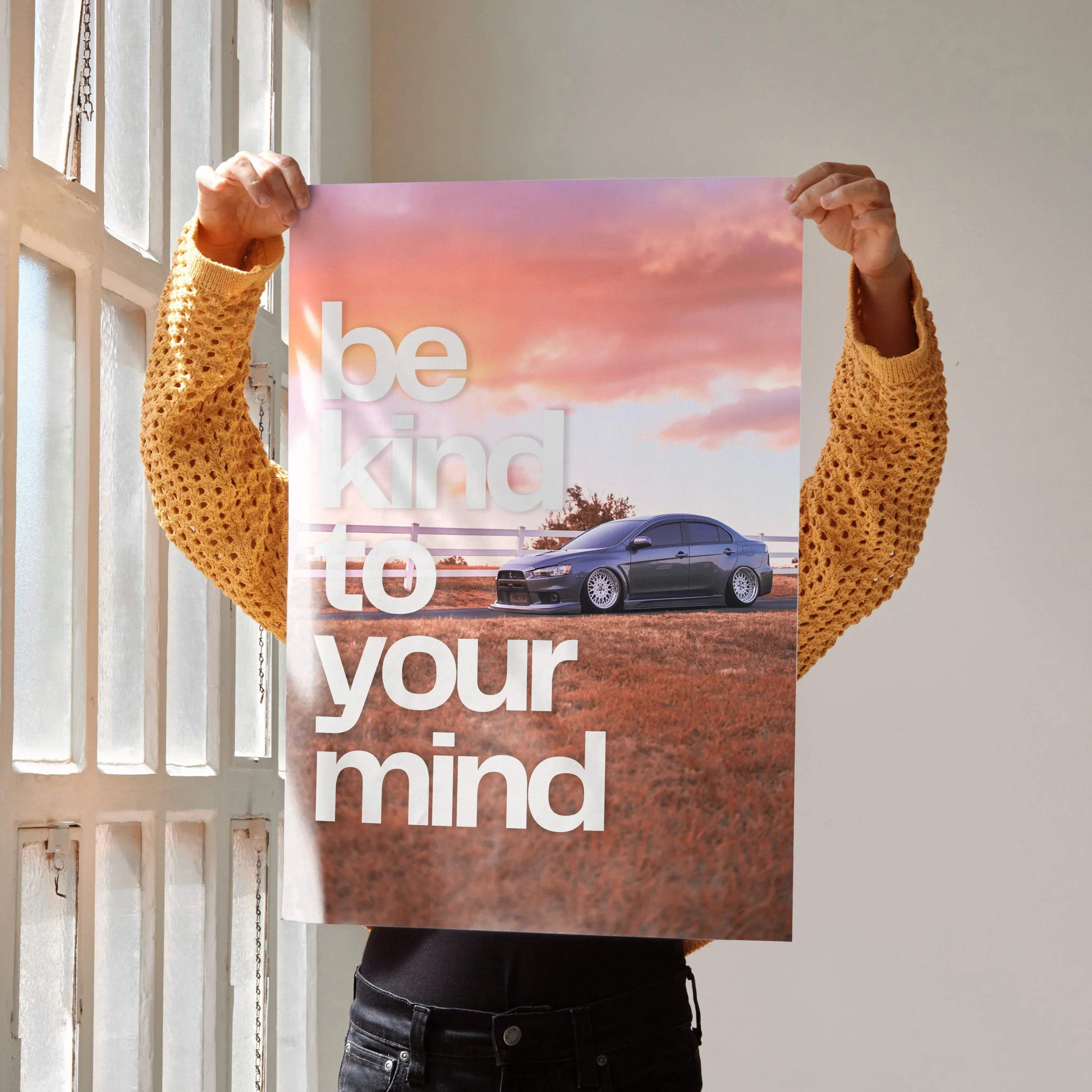 Poster wall art with a blue Mitsubishi Evo 10 under a pink and orange sunset sky and the text "be kind to your mind".