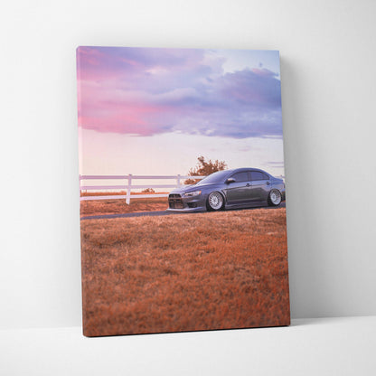 Mitsubishi Evo 10 parked on brown grass under pink and purple sunset sky canvas wall art.