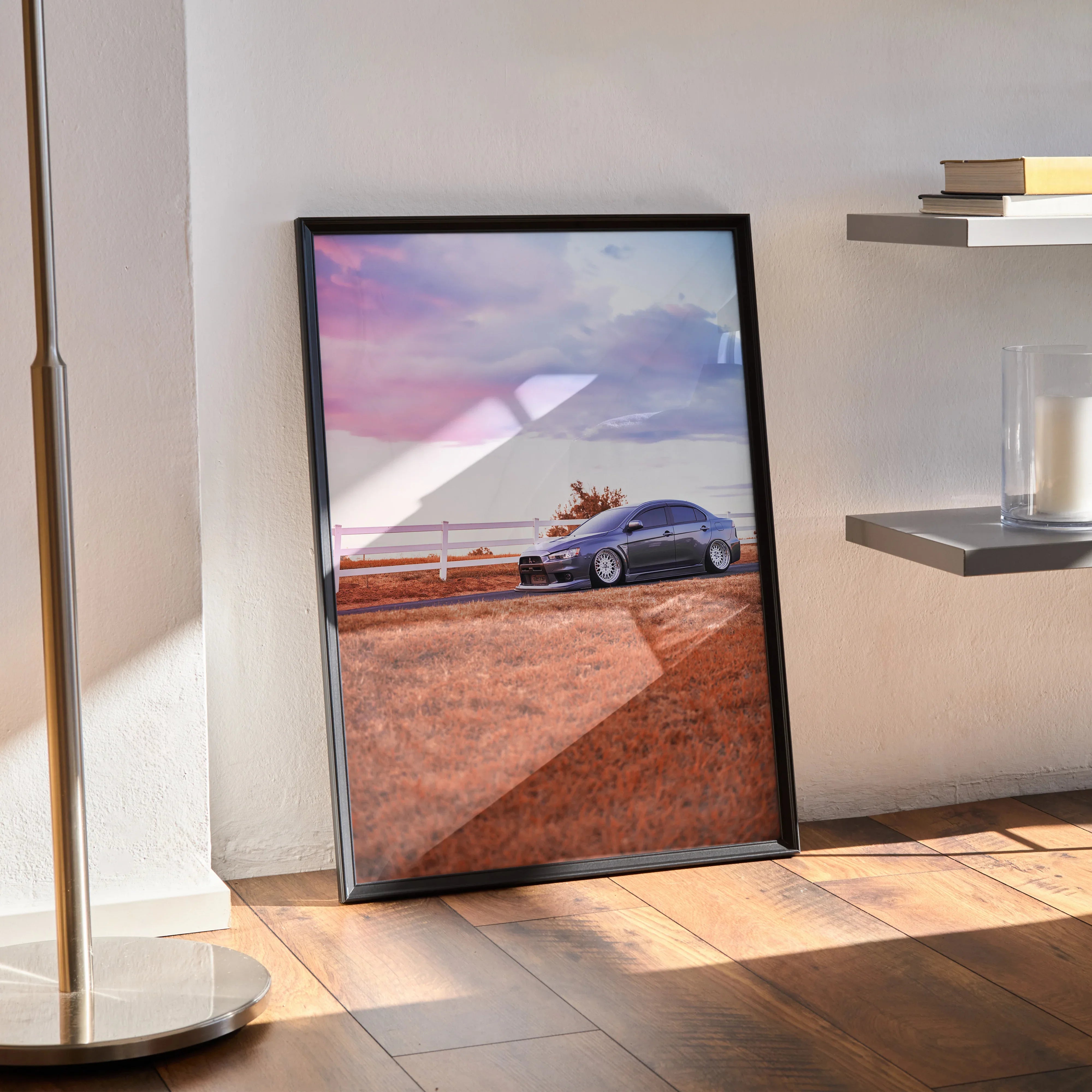 Mitsubishi Evo 10 poster wall art with sunset background in black frame leaning on floor.