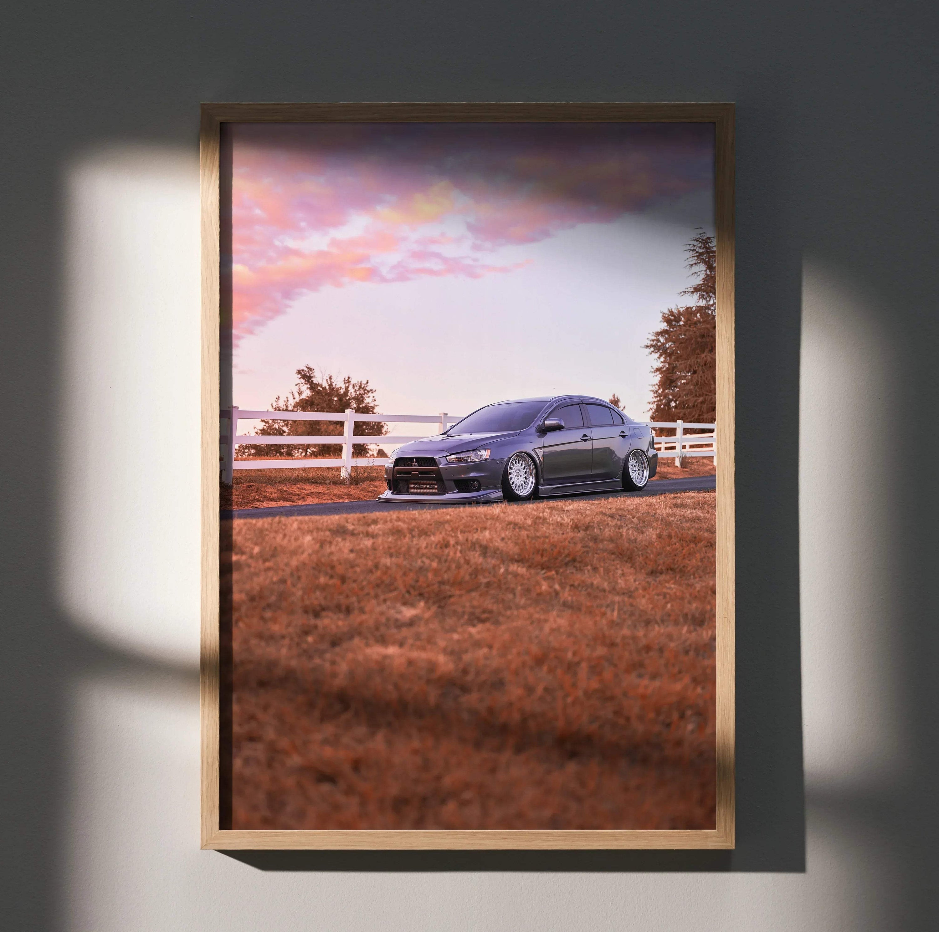 Mitsubishi Evo 10 parked on grassy field under pink sky, framed poster wall art.