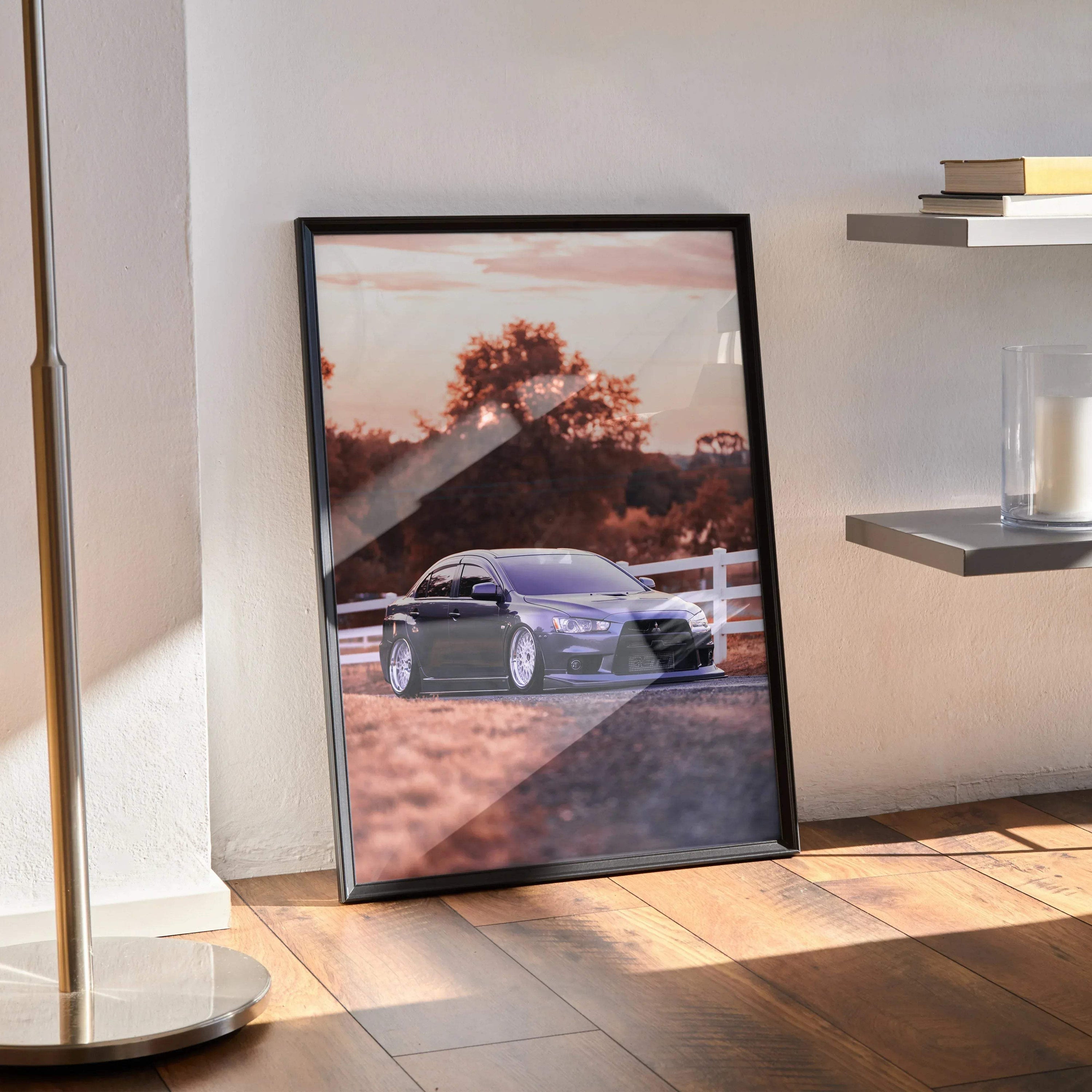 Mitsubishi Evo 10 poster wall art featuring a sleek silver car parked by a white fence at sunset with warm tones.